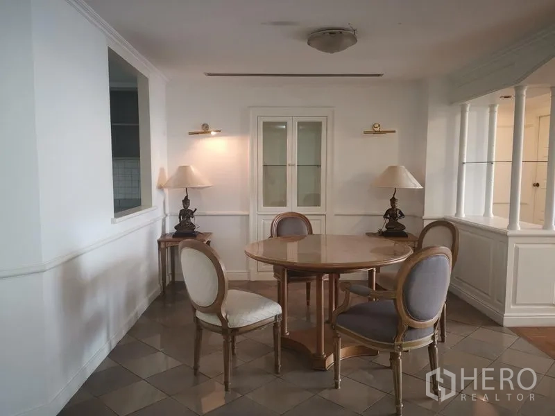 Condominium for rent in Watthana, Bangkok - Classic dining nook with round wooden table, four upholstered chairs, and display cabinet.
