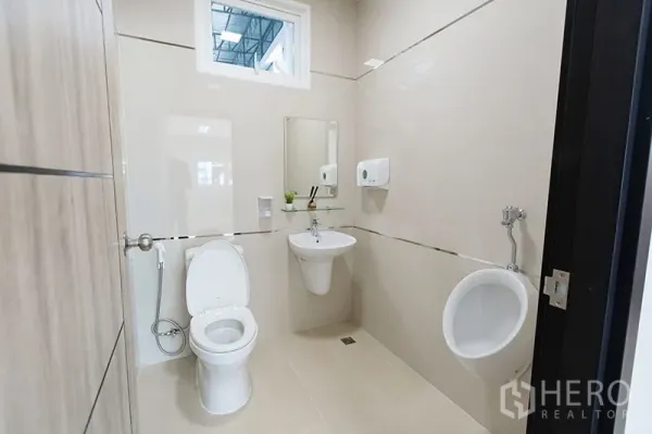 Warehouse for rent in Bang Bo, Samut Prakan - Clean industrial restroom with toilet, urinal and wall-mounted sink inside the warehouse office.