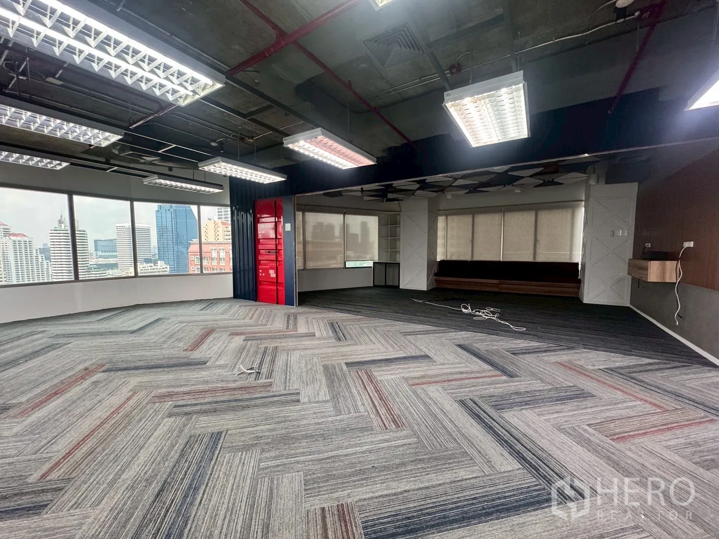 办公室 for rent in Watthana, Bangkok - 转角办公区，大窗外可见城市天际线，配红色特色墙面。