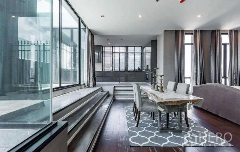 Condominium for rent - Open dining area with wood-slab table and steps leading toward the kitchen.