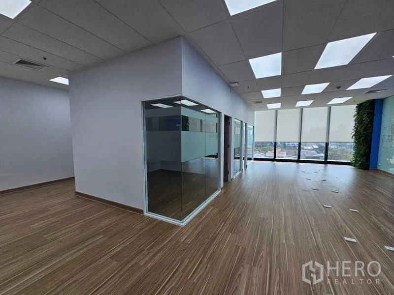 Office Space for rent in Sathon, Bangkok - Corner corridor of glass-partitioned offices leading to city-view windows with roller shades.