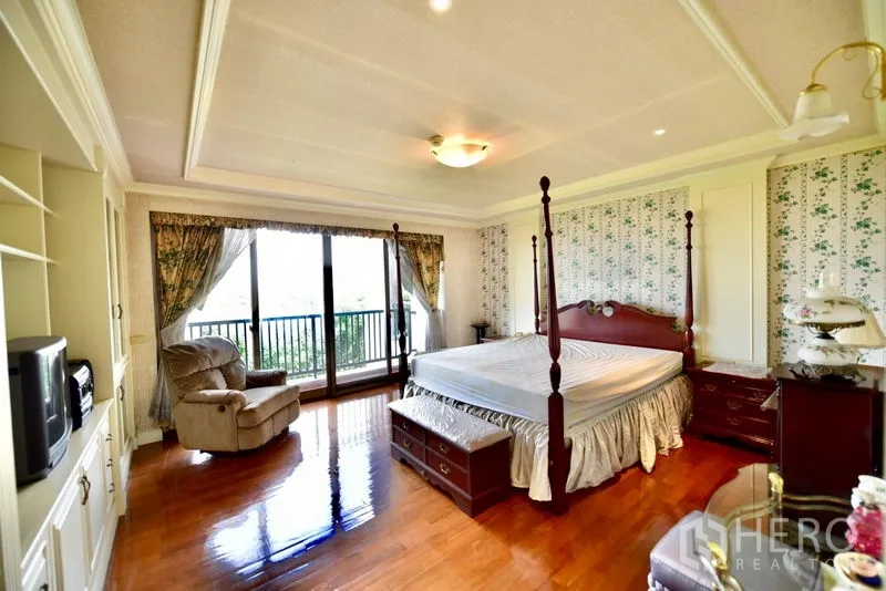 คอนโด ขายในPak Kret, Nonthaburi - ห้องนอนใหญ่เตียงสี่เสา ตู้บิ้วท์อิน เก้าอี้เอน และทางออกสู่ระเบียง