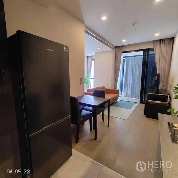 Condominium for rent in Watthana, Bangkok - Compact kitchen with black fridge, two-seat dining table and view to the lounge and balcony.