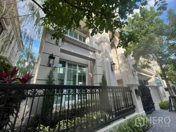 บ้าน ขายในYan Nawa, Bangkok - ด้านหน้าบ้านเดี่ยวสไตล์หรู ผนังสีครีม รั้วเหล็กดำ และสวนหย่อมร่มรื่น ในย่านช่องนนทรี