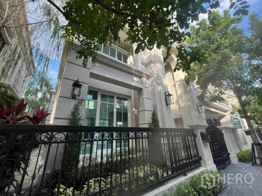 บ้าน ขายในYan Nawa, Bangkok - ด้านหน้าบ้านเดี่ยวสไตล์หรู ผนังสีครีม รั้วเหล็กดำ และสวนหย่อมร่มรื่น ในย่านช่องนนทรี