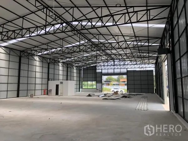 Warehouse for rent in Pak Kret, Nonthaburi - High-clearance warehouse interior with steel truss roof, skylights and large shutter doors.