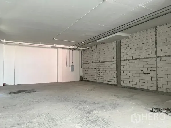 零售空间 出租 - 未装修商铺，裸露砌块墙、顶置管线与混凝土地面。