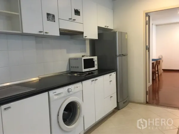 Condominium for rent or sale in Watthana, Bangkok - White cabinetry kitchen featuring a cooktop, washing machine, microwave and tall refrigerator.