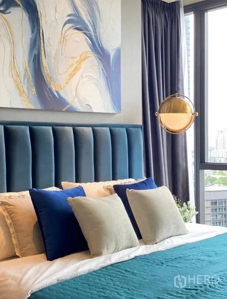公寓 出租 - 蓝色床头与多层靠枕特写，抽象画与高窗相映成趣。