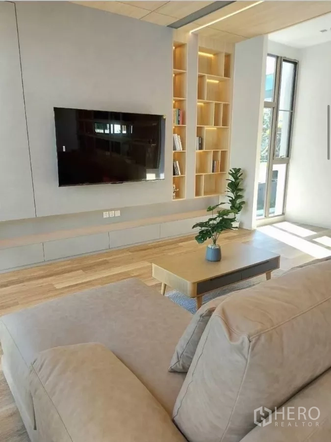 Detached House for rent in Saphan Sung, Bangkok - TV wall with floating console, illuminated shelves and wide plank wood floors in the living area.