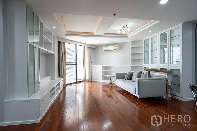 公寓 出售在Watthana, Bangkok - 采光良好的客厅，层次天花、沙发、展示柜与阳台入口。