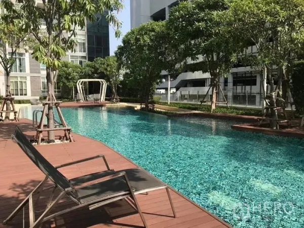 Condominium for rent or sale - Resort-style outdoor swimming pool with sun deck and trees at the condominium.