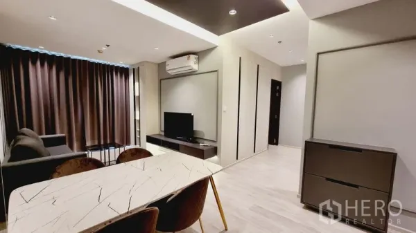 คอนโด ขายในWatthana, Bangkok - พื้นที่นั่งเล่นและรับประทานอาหารสไตล์โมเดิร์น มีโต๊ะหินอ่อน โซฟา ชั้นวางทีวี และผ้าม่านทึบ