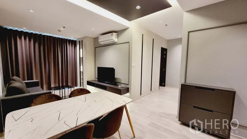 คอนโด ขายในWatthana, Bangkok - พื้นที่นั่งเล่นและรับประทานอาหารสไตล์โมเดิร์น มีโต๊ะหินอ่อน โซฟา ชั้นวางทีวี และผ้าม่านทึบ