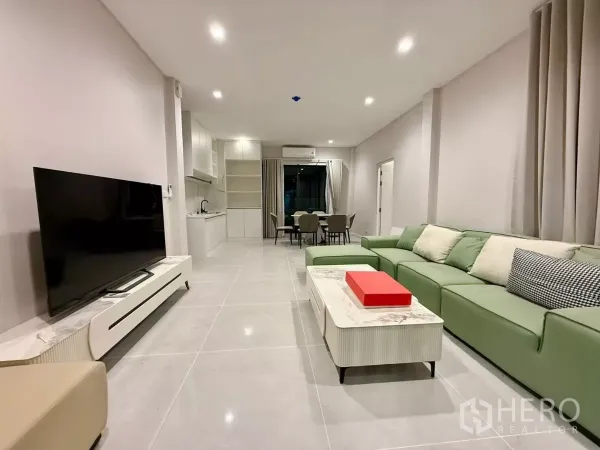 Detached House for rent in Bang Phli, Samut Prakan - Bright open-plan living room with green sectional sofa, TV console and recessed lighting.
