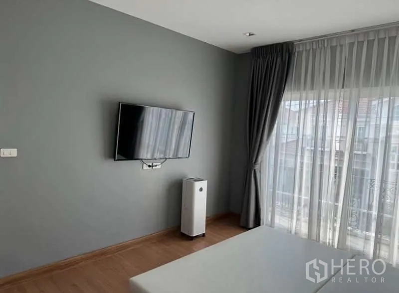 Detached House for rent in Bueng Kum, Bangkok - Bedroom wall with mounted TV, air purifier and balcony doors with curtains.