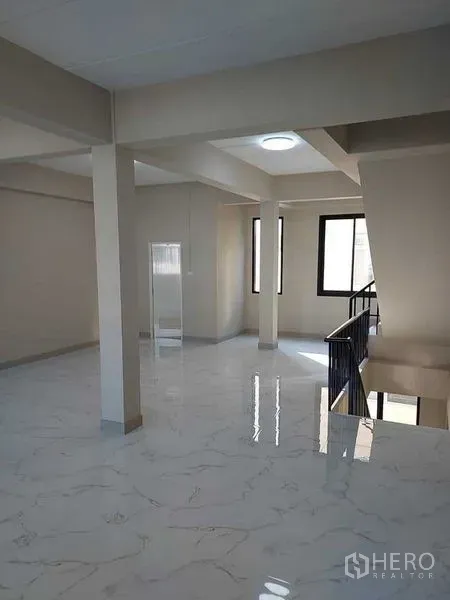 Shophouse for rent in Bang Kapi, Bangkok - Bright open-plan upper floor with marble-look tiles, support columns, and large windows.