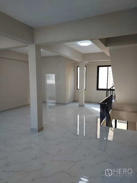 Shophouse for rent in Bang Kapi, Bangkok - Bright open-plan upper floor with marble-look tiles, support columns, and large windows.