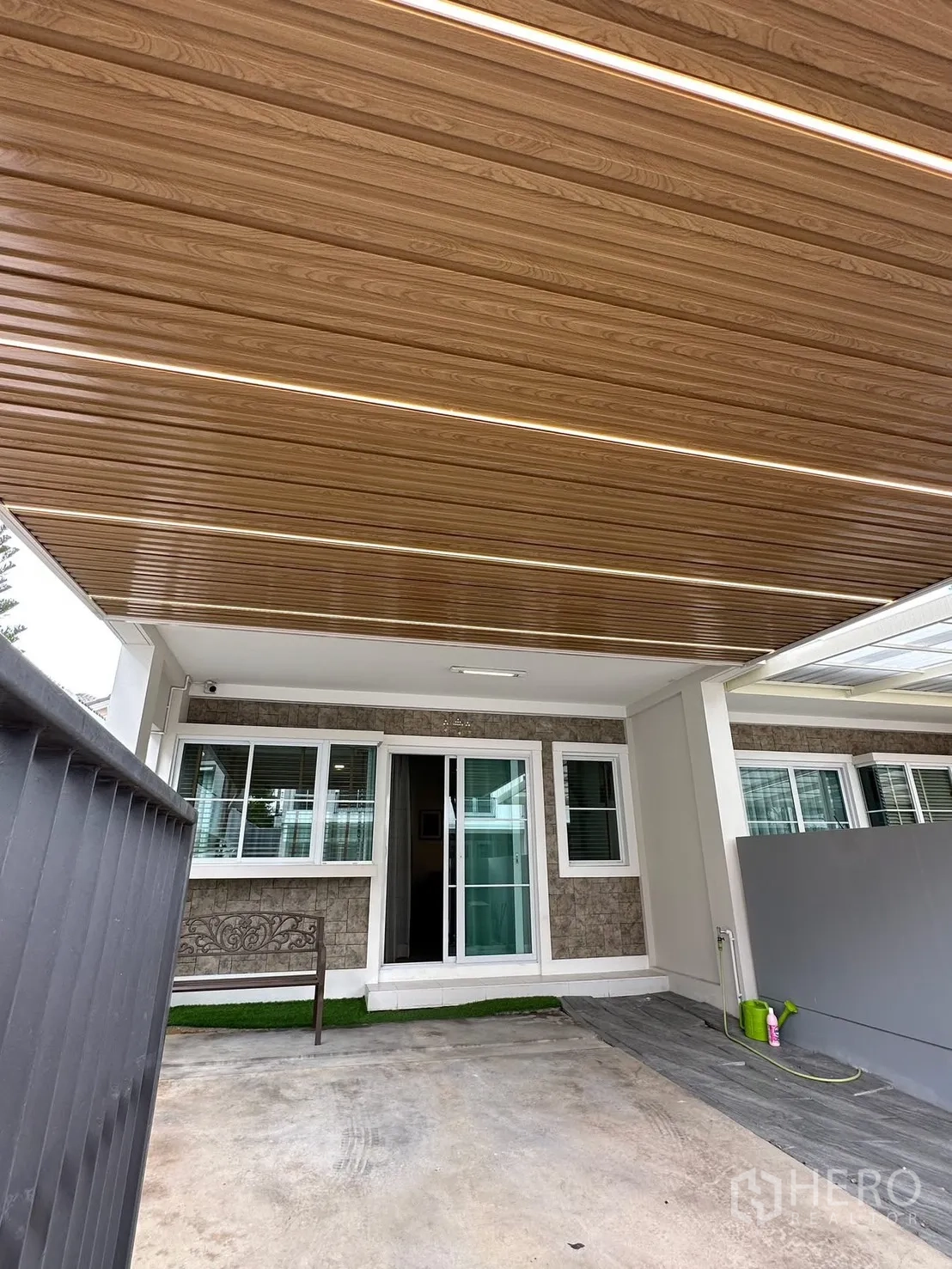联排别墅 for rent in Prawet, Bangkok - 带木纹顶棚的遮雨车位，配有入户推拉玻璃门和窗户。