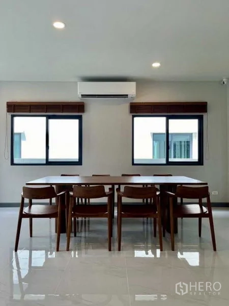 独立式住宅 出租在Bang Phli, Samut Prakan - 采光充足的餐区，木质餐桌八把椅子，两扇窗与空调。