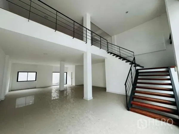 Home Office for rent in Bueng Kum, Bangkok - Double-height open-plan ground level with glossy tiles and a steel staircase leading to the mezzanine.