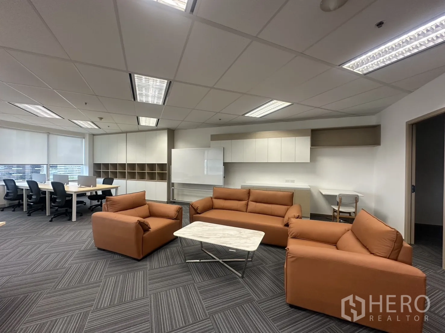 办公室 for rent in Pathum Wan, Bangkok - 休闲区有扶手椅、沙发与大理石茶几，邻近工位区。