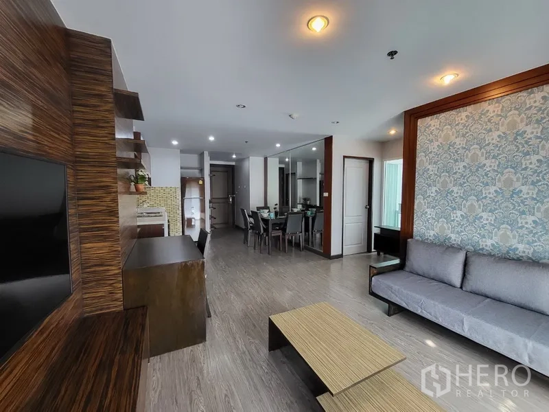 Condominium for rent in Phra Khanong, Bangkok - Spacious living–dining area facing the kitchen, mirrored wall, and modern lighting.