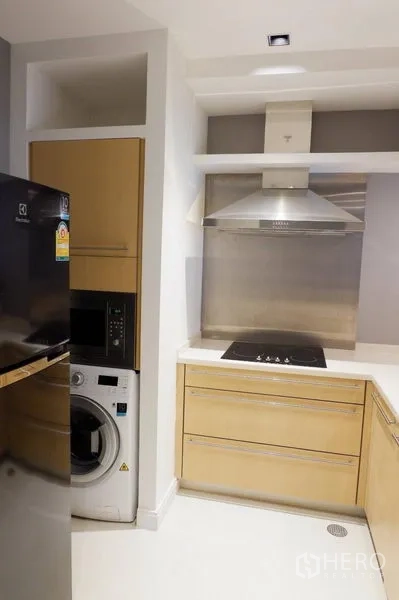 Condominium for rent in Pathum Wan, Bangkok - Compact kitchen with stovetop, range hood, refrigerator and washer-dryer.