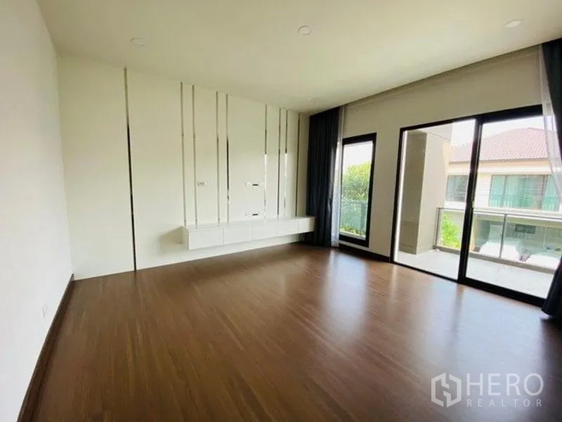 Detached House for sale in Bang Phli, Samut Prakan - Bright bedroom with wood floors and sliding glass doors opening to a balcony.