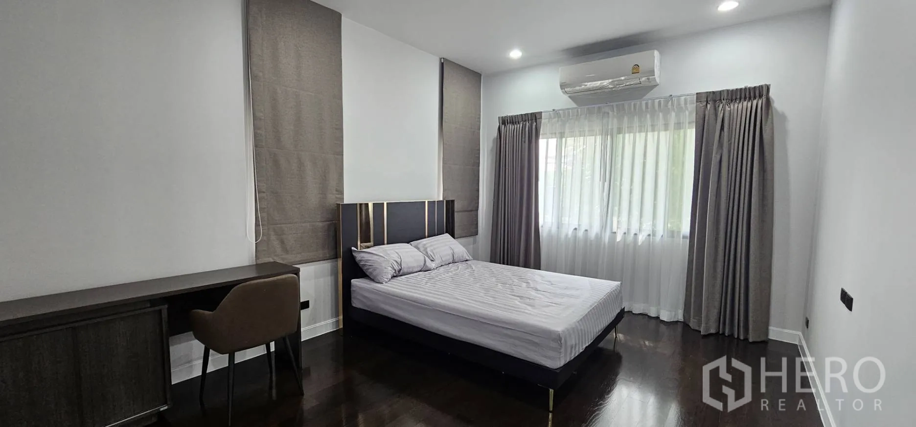Detached House for rent in Bang Kapi, Bangkok - Bedroom with double bed, long desk and dark wood floors.