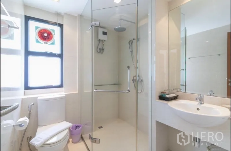 房间 出租在Bang Rak, Bangkok - 整洁浴室，玻璃淋浴间、顶喷花洒、盥洗台与坐厕。