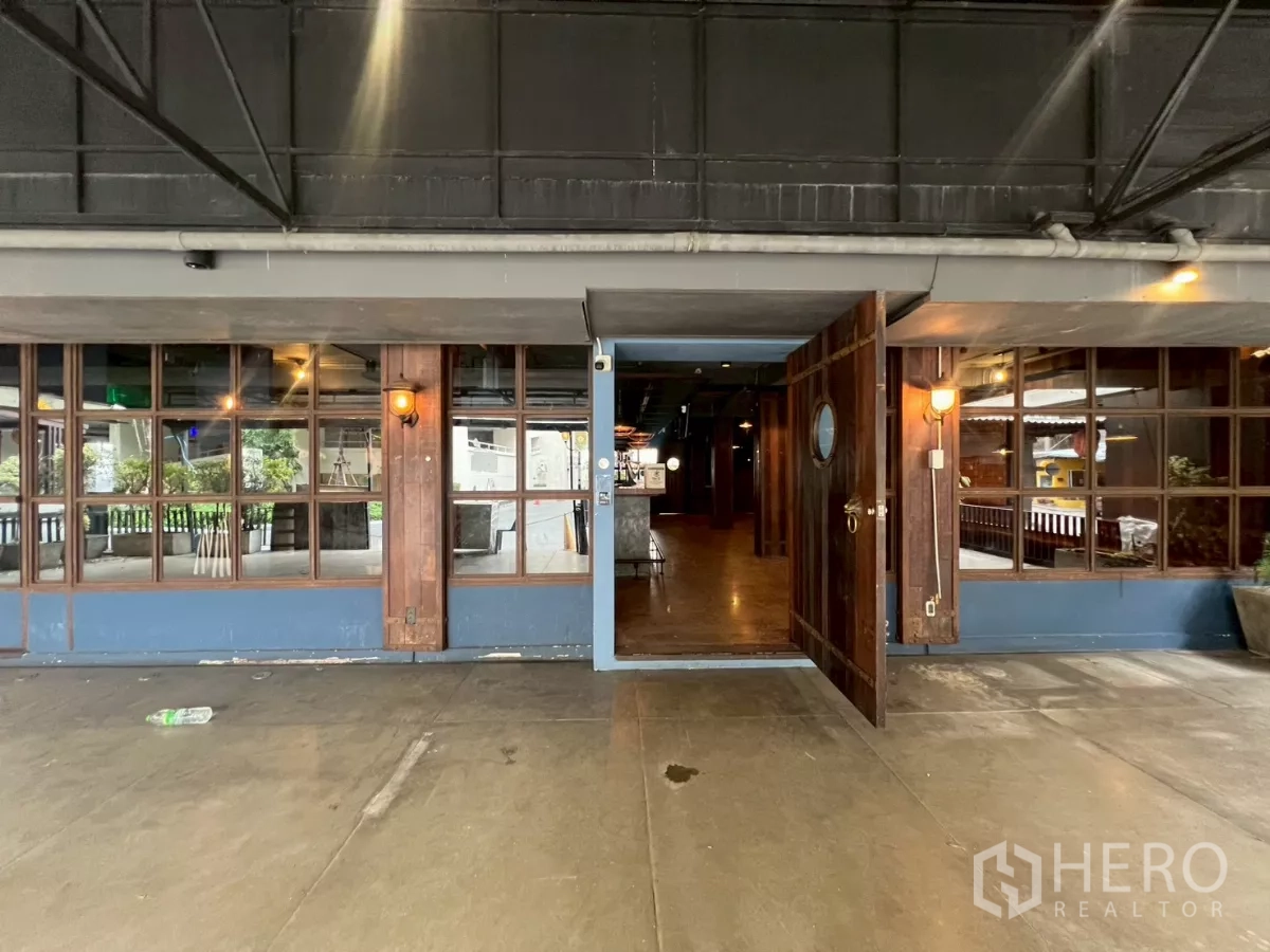 零售空间 出租 - 带顶棚的店面，木质双开门与格栅窗通向宽敞室内。