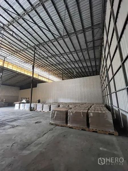 Warehouse for rent in Rat Burana, Bangkok - Open-plan storage area with corrugated walls, high clearance and stacked pallets.