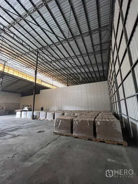 Warehouse for rent in Rat Burana, Bangkok - Open-plan storage area with corrugated walls, high clearance and stacked pallets.