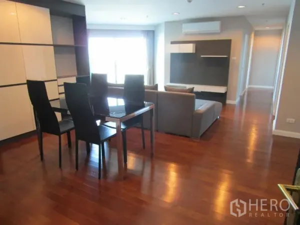 Condominium for sale in Huai Khwang, Bangkok - Open-plan living and dining area with wooden floors, gray sofa, and glass dining table