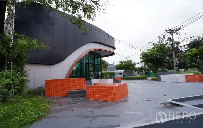 独立商业地产 出租在Bang Na, Bangkok - 前广场设橙色瓷砖座椅，建筑外立面曲线感强。