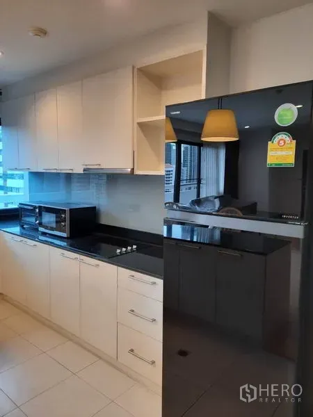 公寓 出租在Watthana, Bangkok - 厨房特写，内置橱柜、亮黑色冰箱与家电齐全。