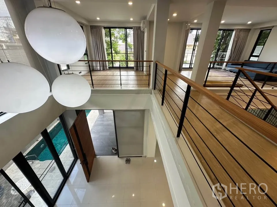 Detached House for sale in Watthana, Bangkok - View from the mezzanine to the entry void with pendant lights and terrace.