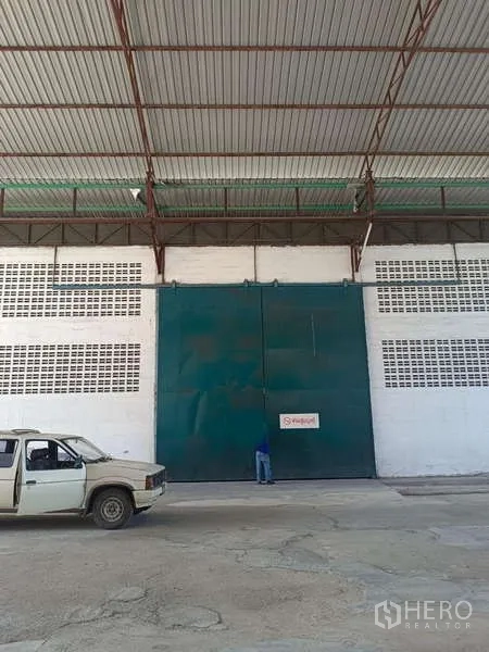 货栈 出租在Mueang Rayong, Rayong - 仓库立面上的高大绿色滑门，位于金属雨棚下。