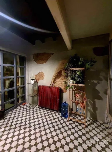 Detached House for rent in Pathum Wan, Bangkok - Night view of the terrace with patterned tiles, bamboo decor and plants by a textured wall.