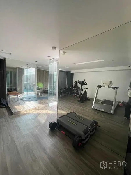 Condominium for rent in Watthana, Bangkok - Fitness room featuring treadmill, exercise bike, step platforms and full-height mirrors.