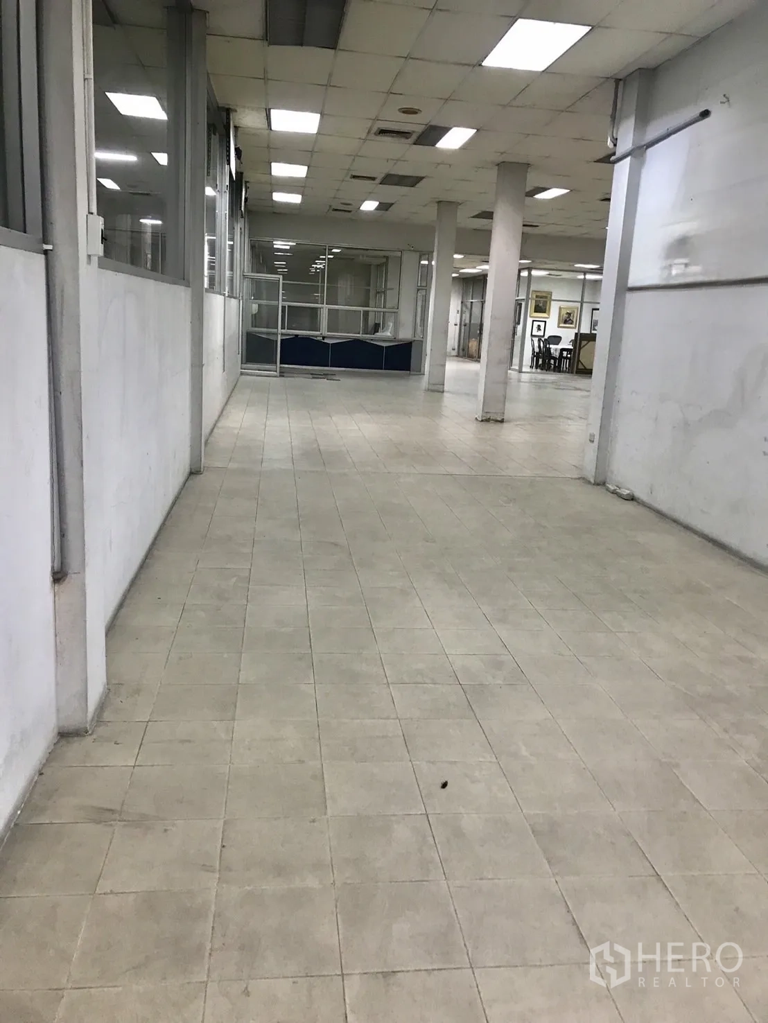仓库 for rent in Phra Khanong, Bangkok - 长形室内工作区，瓷砖地面、柱体与荧光灯天花及隔断间。