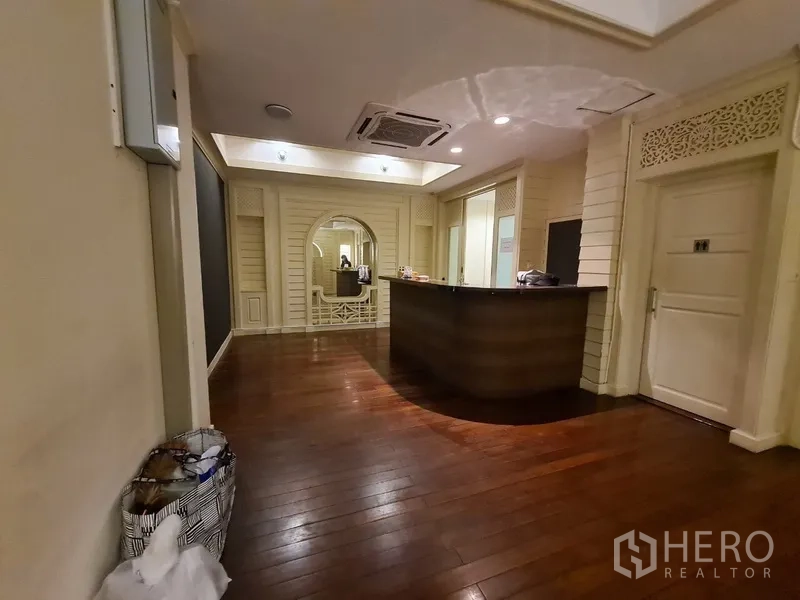 店屋 出租在Khlong Toei, Bangkok - 接待区，弧形前台、深色实木地板、拱形装饰墙与筒灯。