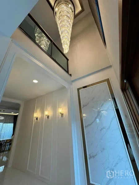 บ้าน ให้เช่าหรือขายในBang Na, Bangkok - โถงเพดานสูงสองชั้น ประดับโคมไฟคริสตัลและโคมติดผนัง