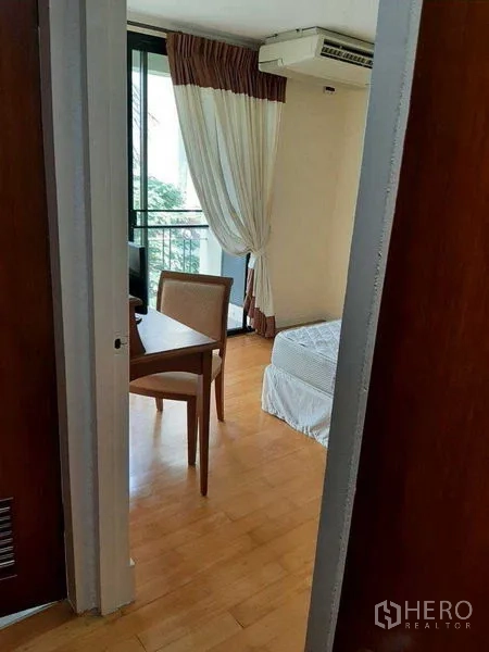 อพาร์ทเมนท์ ให้เช่าในWatthana, Bangkok - ห้องนอนอบอุ่นพร้อมโต๊ะทำงานข้างระเบียง พื้นไม้ และผ้าม่านยาว
