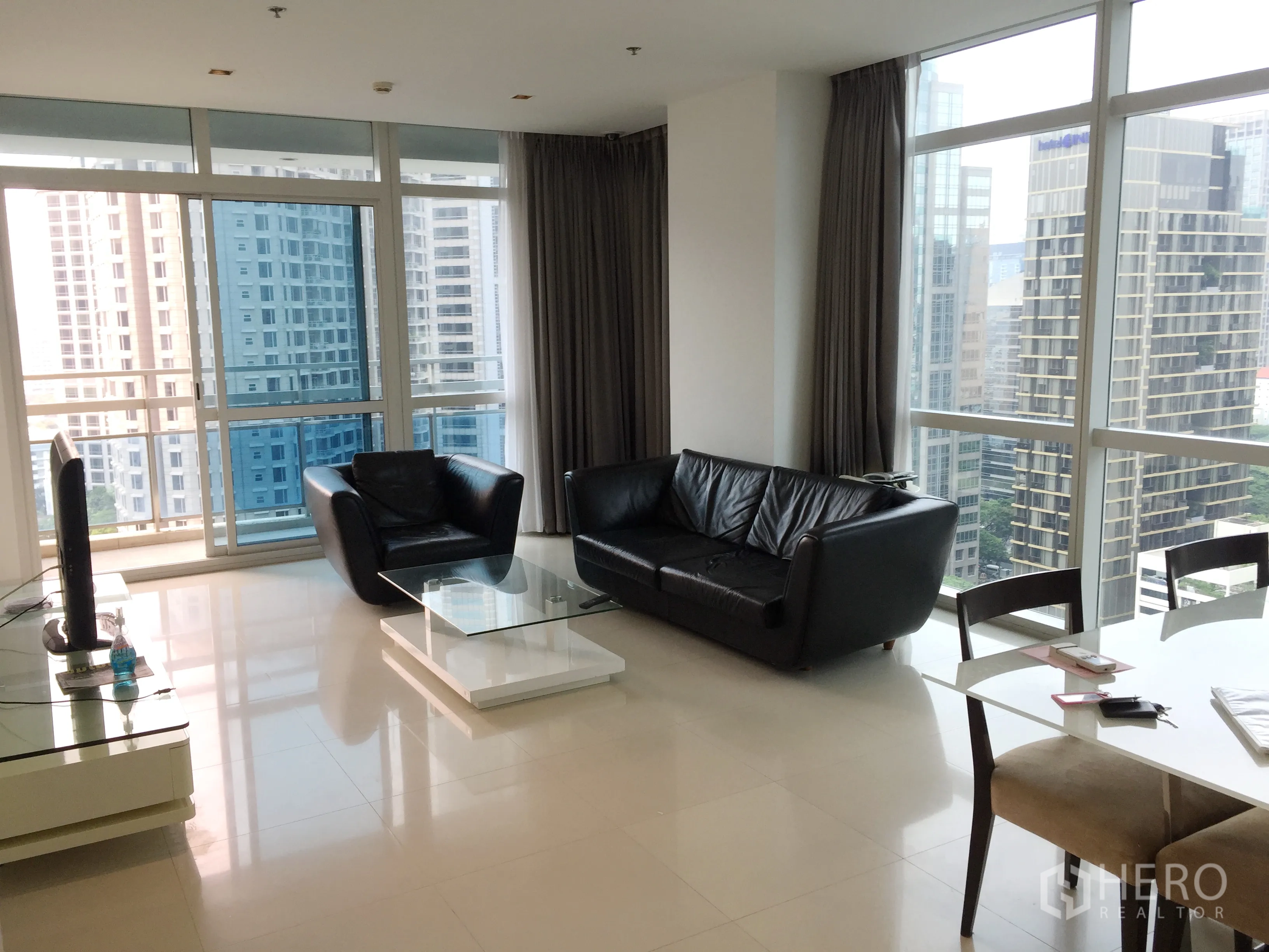 Condominium for rent in Pathum Wan, Bangkok - Bright living room with floor-to-ceiling windows, black leather sofas and skyline views.