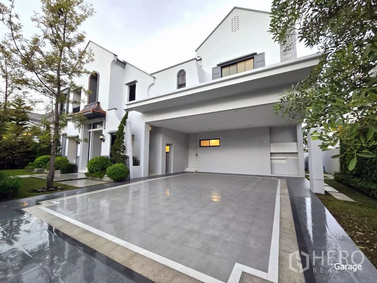 Detached House for rent in Saphan Sung, Bangkok - Spacious covered driveway and four‑car garage beside a landscaped front yard.