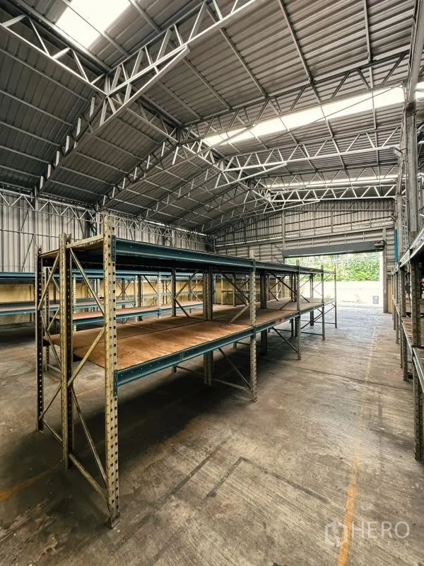 Warehouse for rent in Din Daeng, Bangkok - Long double‑tier racks under skylights facing the loading entrance of the warehouse.