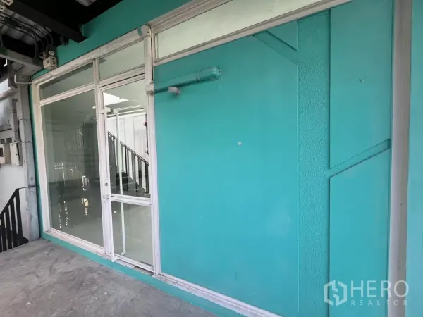 零售空间 出租在Watthana, Bangkok - 青绿色外立面与大面积玻璃店面与店门，位于上层走道。
