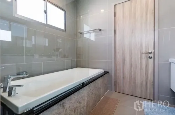 独立式住宅 出租 - 现代卫浴，设浴缸、灰色瓷砖墙与采光窗。